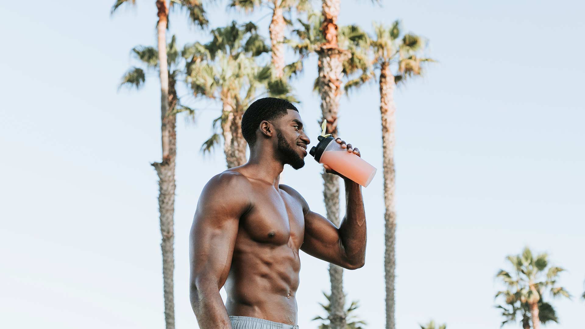 athlete drinking whey protein isolate shake in a a scene full of palm trees